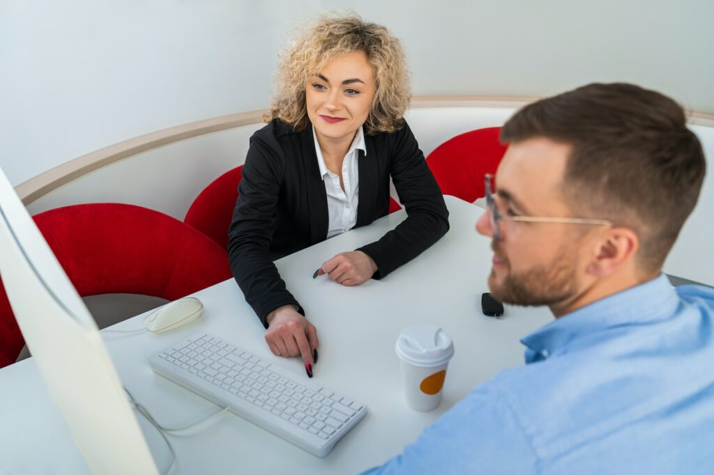 Car dealership manager with client at computer in showroom