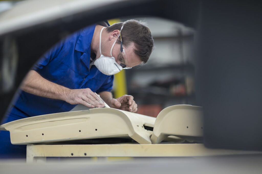 Car mechanic sanding car door in repair garage